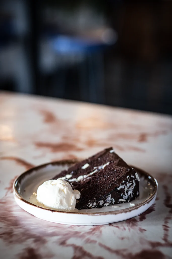 A slice of chocolate cake with ice cream on a marble table at KWB
