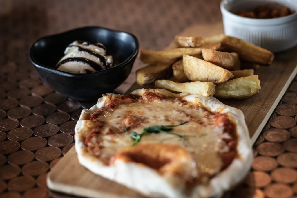 Flatbread pizza, chips and a bowl of dessert on a wooden board at KWB